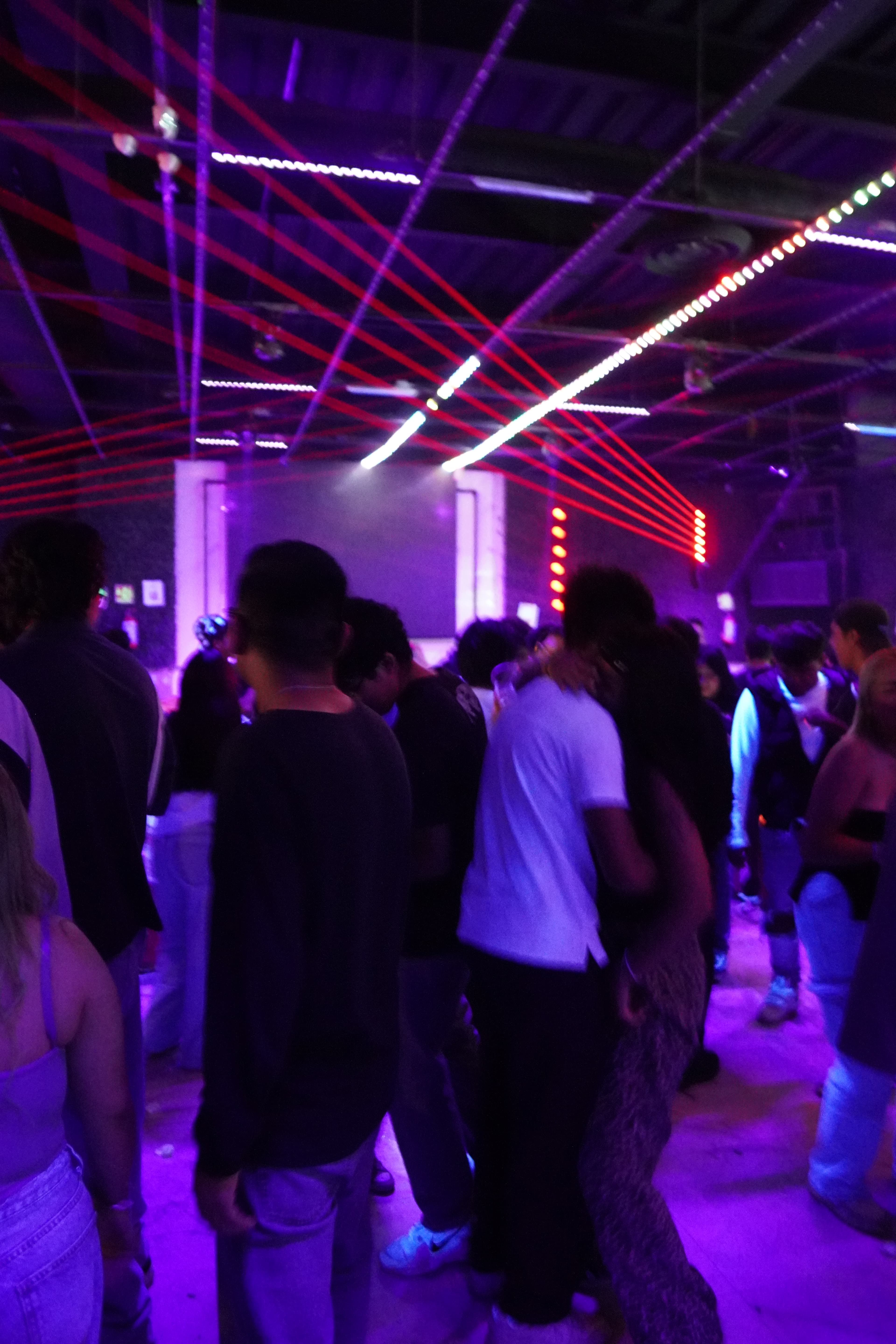 A person holding a vibrant pink cocktail with a neon light in the background.