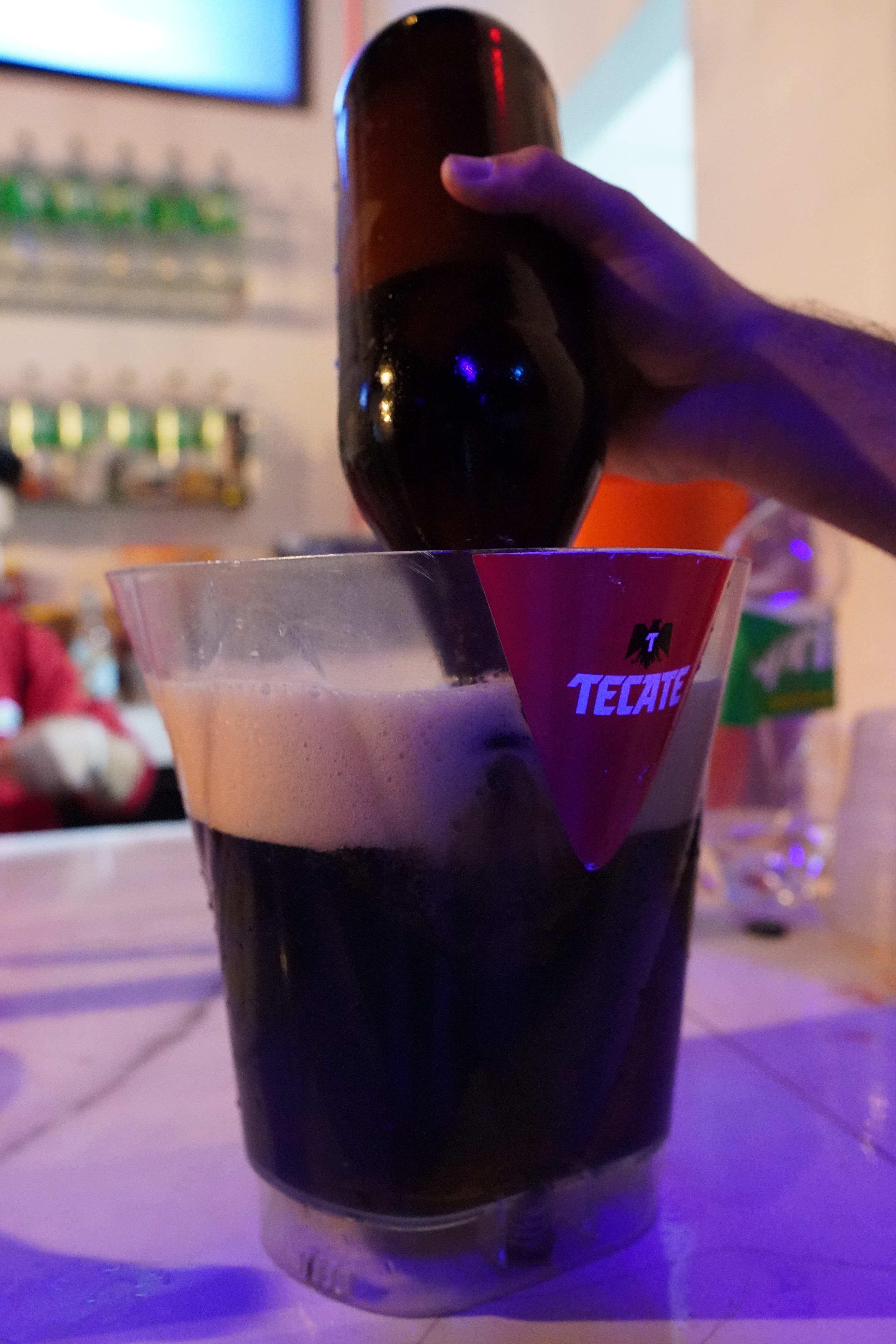 A DJ's hands on a mixer with a lively crowd dancing in the background.