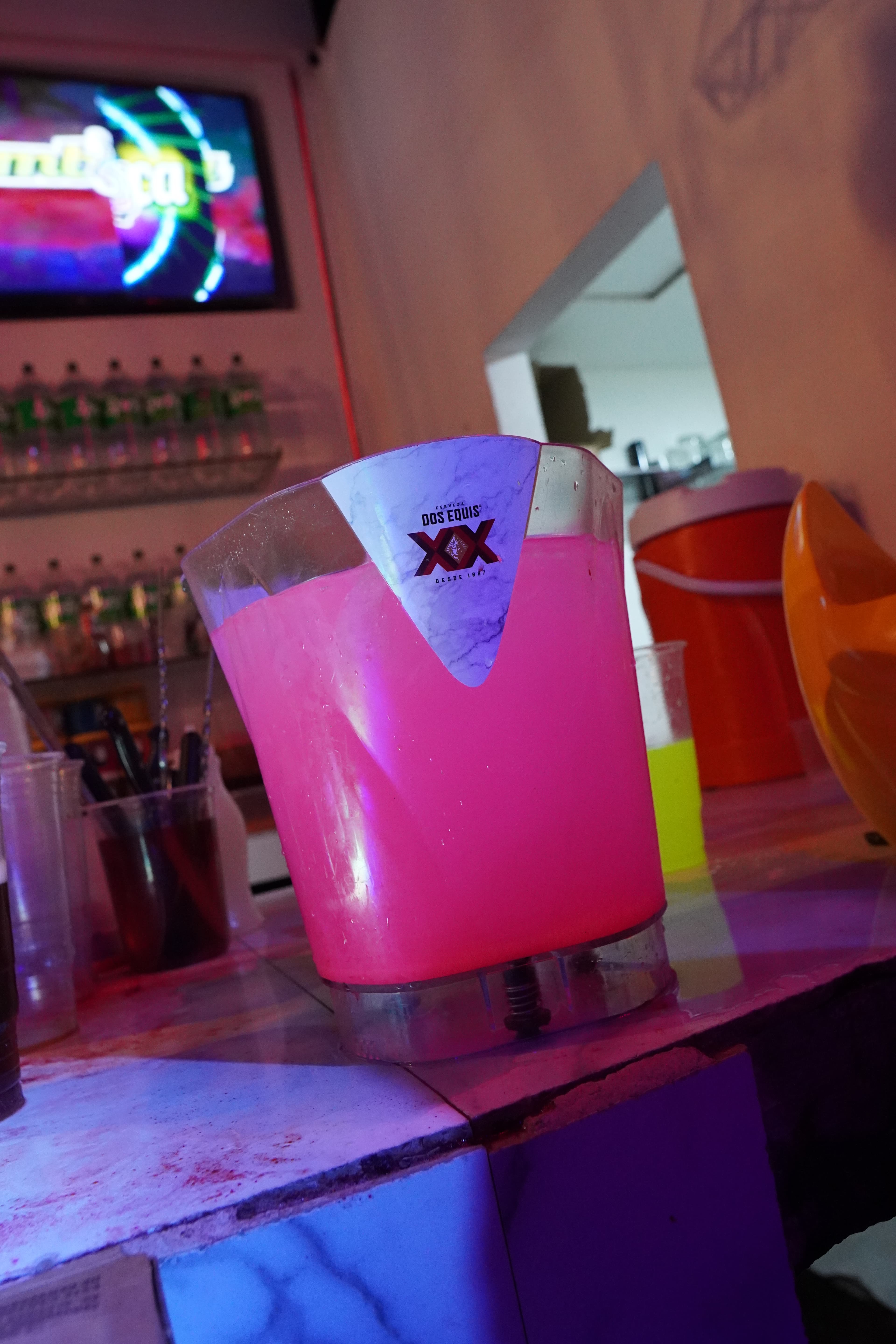 Two people clinking cocktail glasses in a toast at a dimly lit bar.